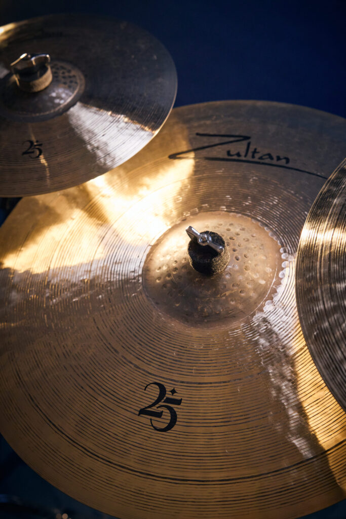 Close-up of golden Zultan 25th Anniversary cymbals, showing the Zultan logo and 25 detail.