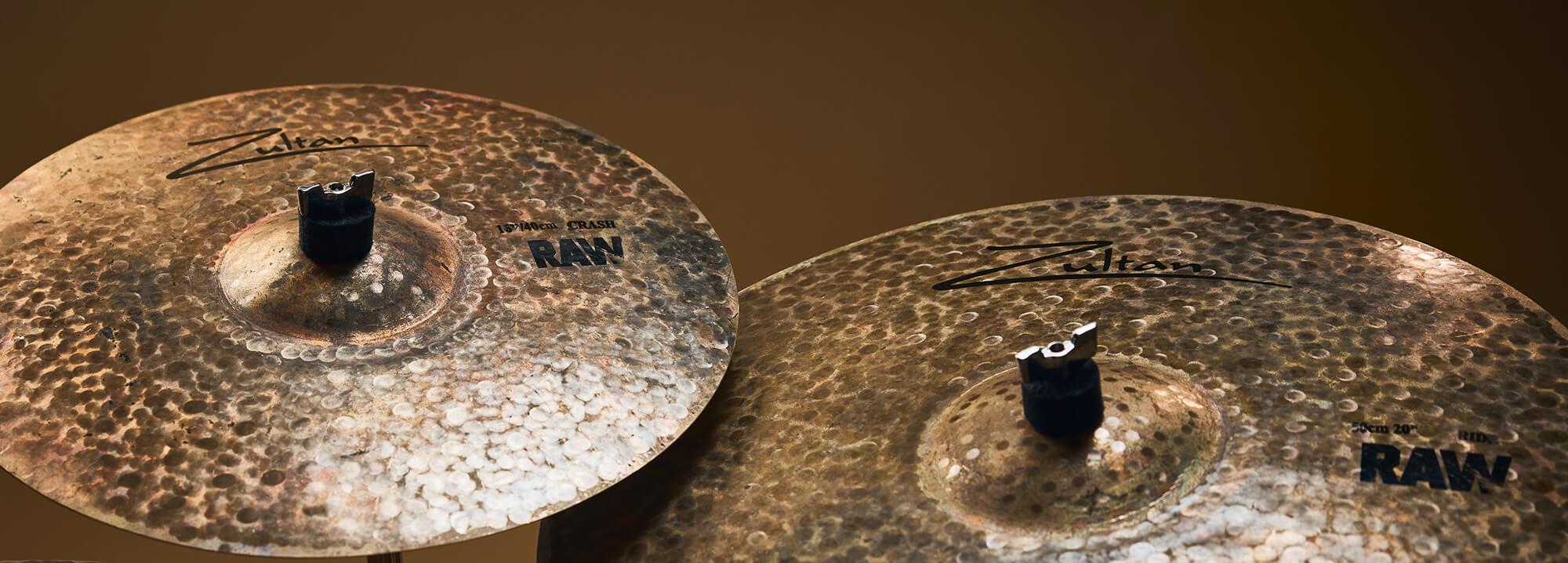 Two Zultan Raw series cymbals, mounted on stands against a warm background.