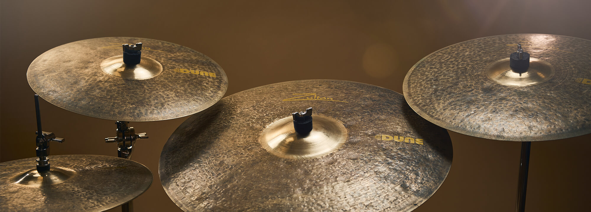 Four Zultan Dune cymbals on stands, angled towards the viewer against a warm-toned background.