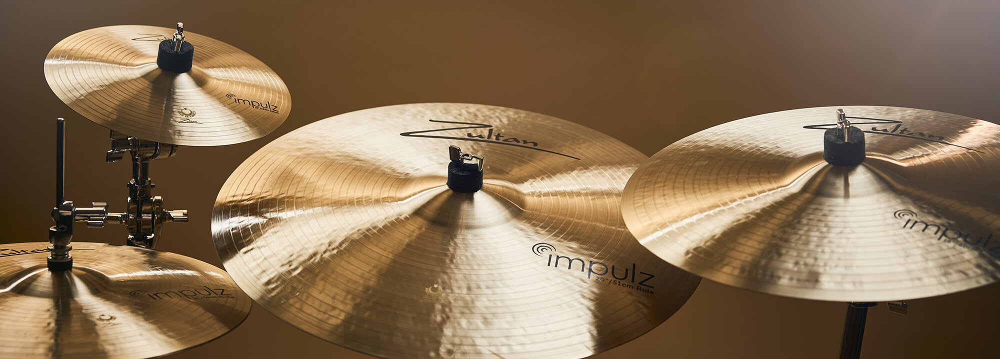 Four Zultan Impulz series cymbals of varying sizes, mounted on stands against a warm background.