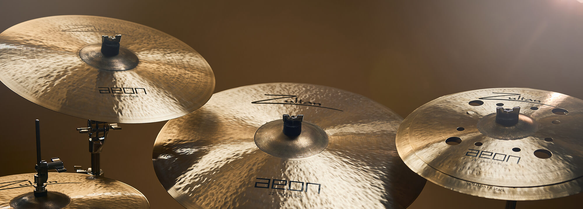 Four Zultan Aeon series cymbals of varying sizes, mounted on stands against a warm background.