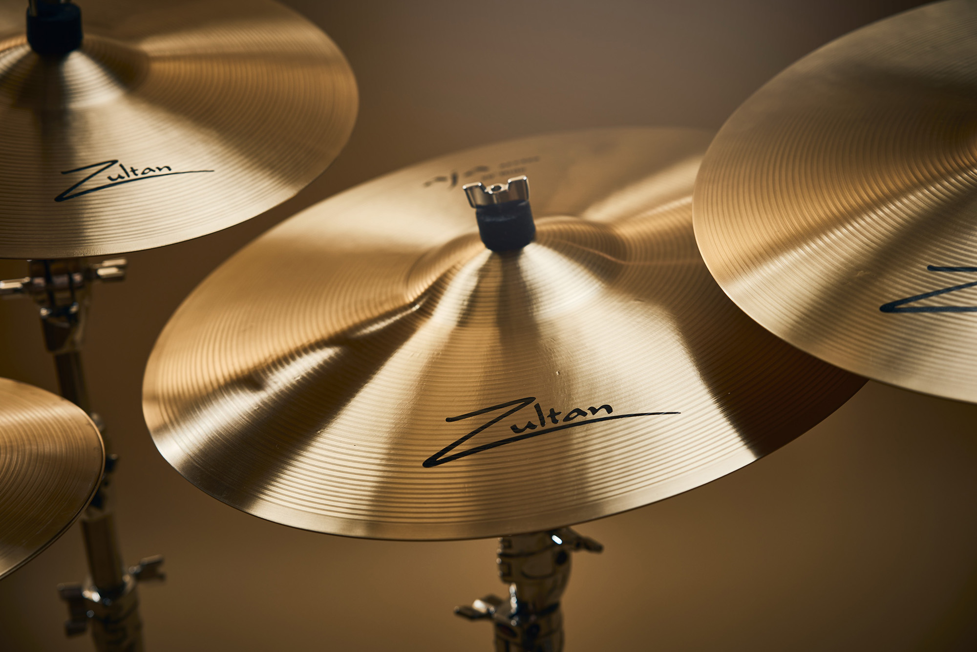 Four Zultan Aja series cymbals of varying sizes, mounted on stands against a warm background.