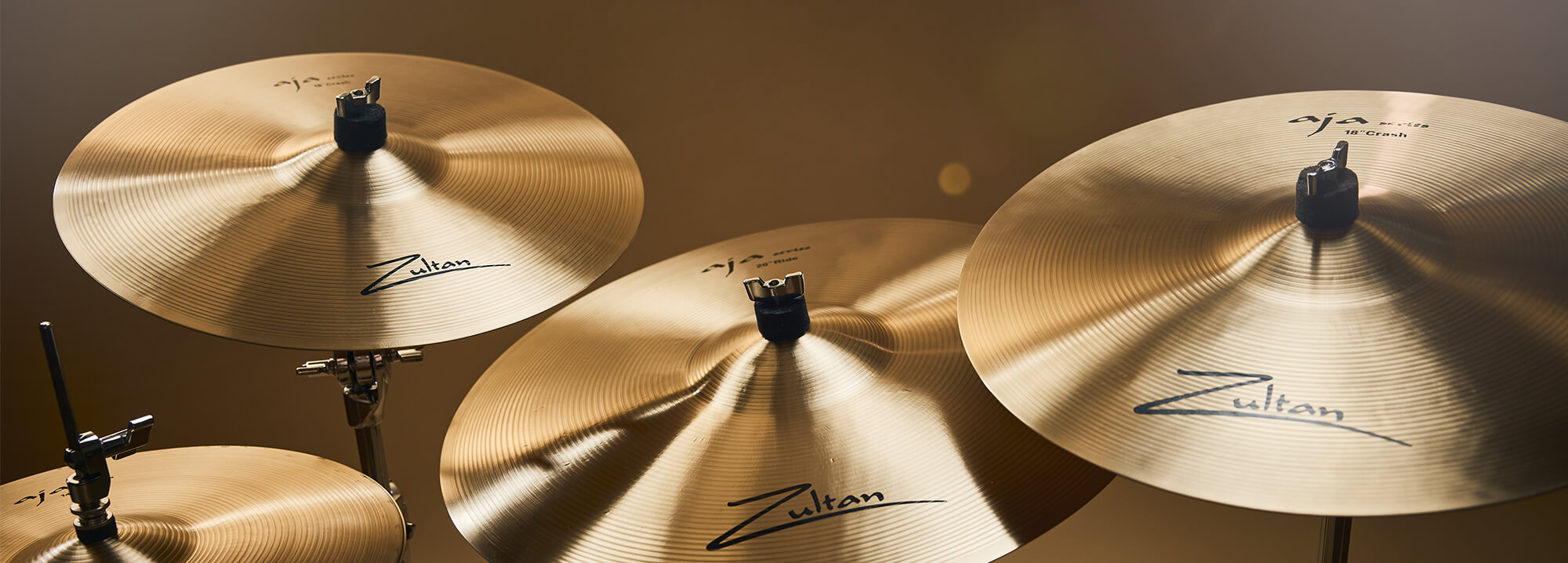 Four Zultan Aja series cymbals of varying sizes, mounted on stands against a warm background.