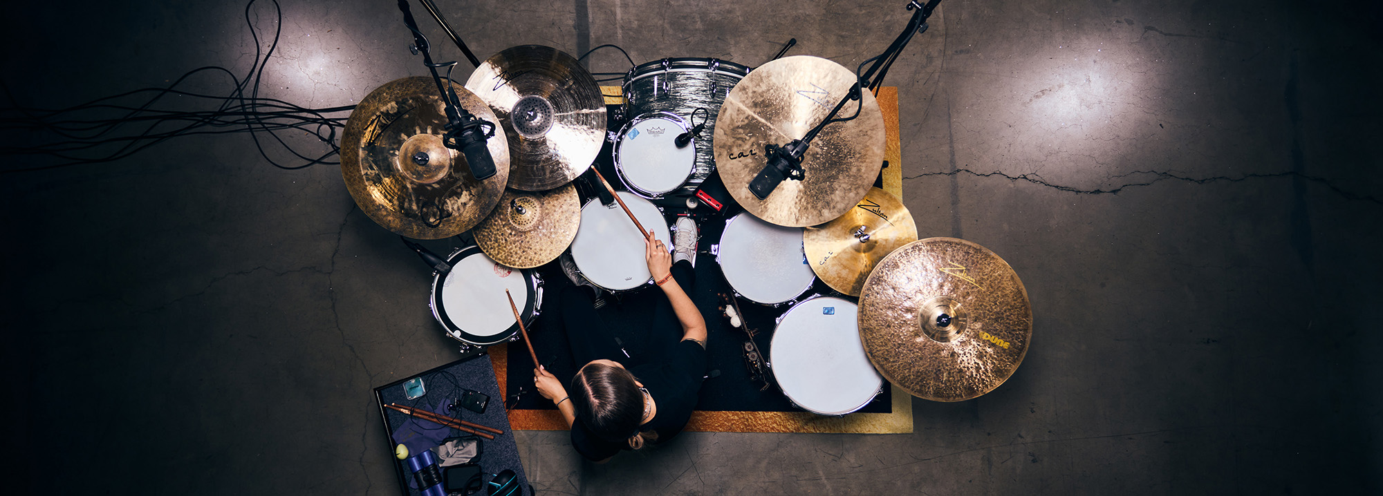 Overhead view of a drummer playing a Zultan drum kit with Caz cymbals on a rug in a studio setting with microphones.