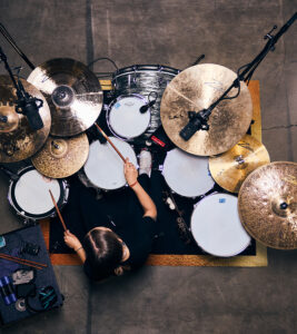Overhead view of a drummer playing a Zultan drum kit with Caz cymbals on a rug in a studio setting with microphones.