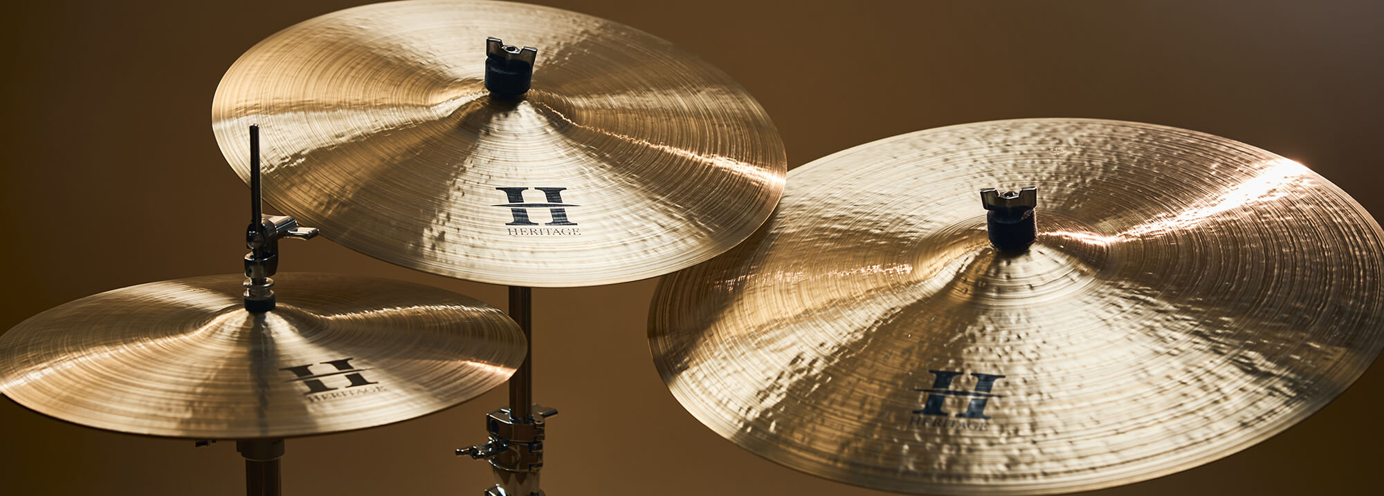 Three Zultan Heritage series cymbals of varying sizes, mounted on stands against a warm background.